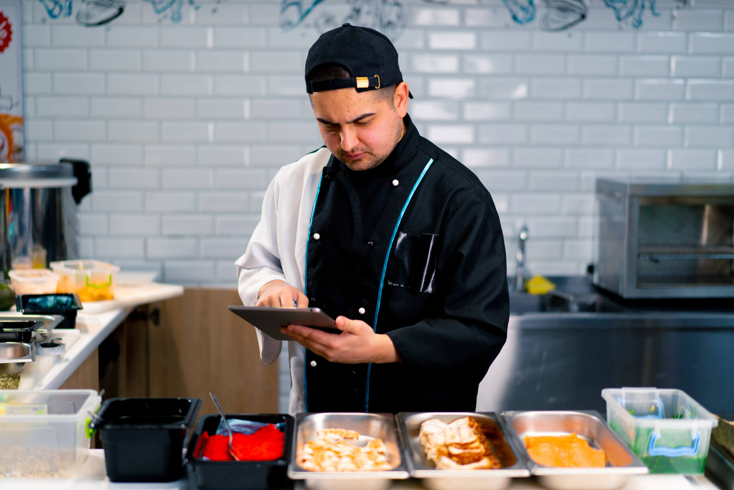 Sushi Chef with a kitchen display in his hands checking the orders
