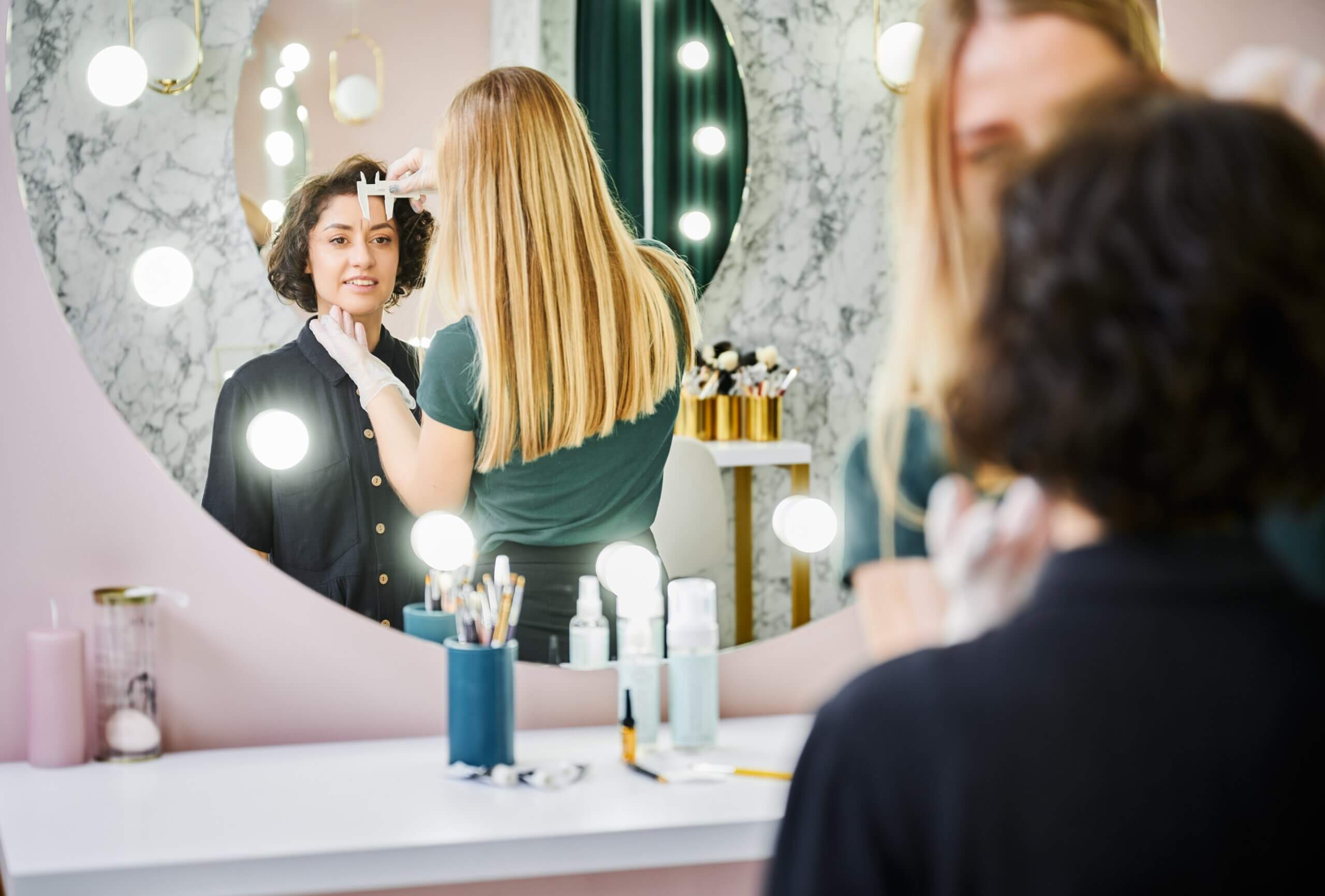 A salon employee measuring a customer's eyebrow length with precision and care.