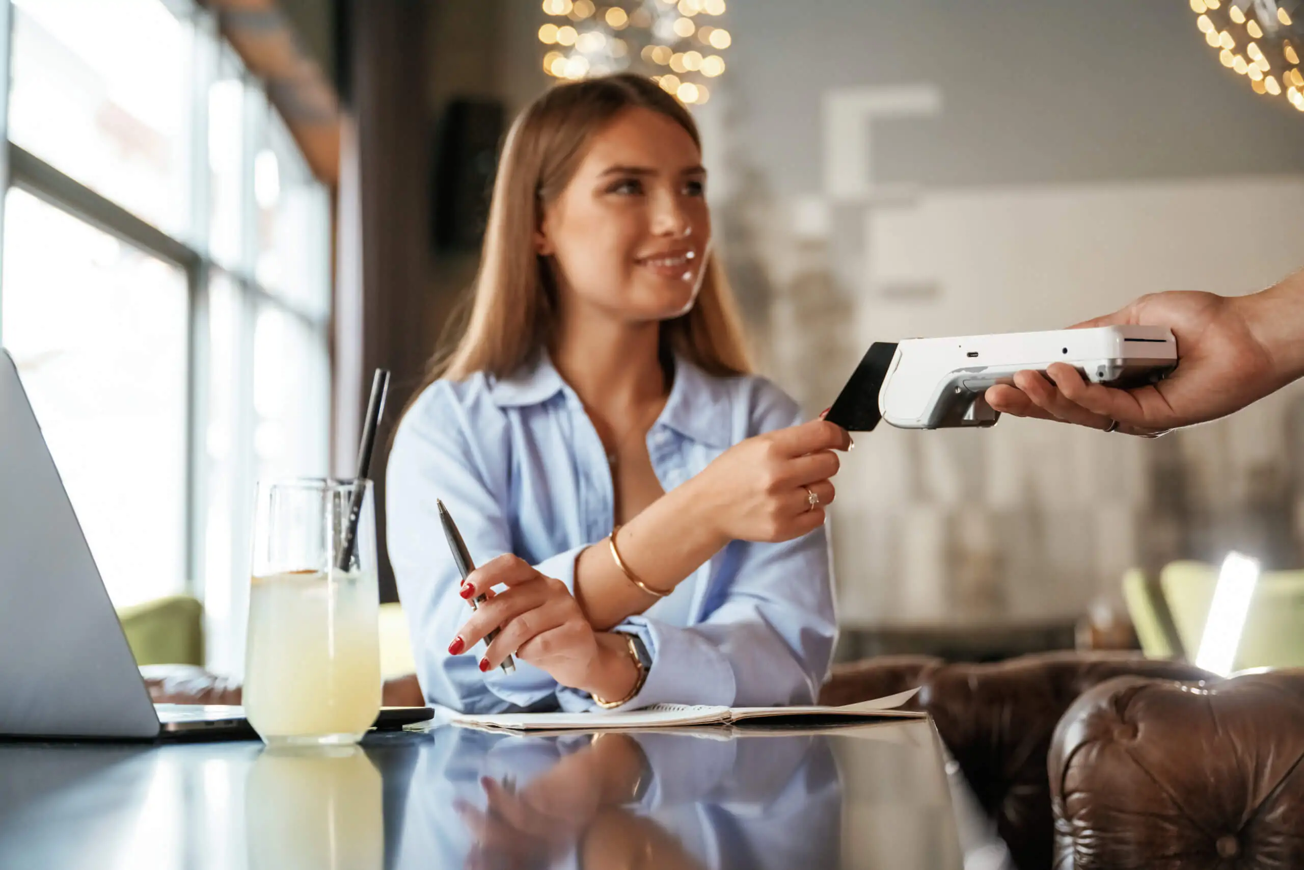 Side view. Woman is paying for the service in the restaurant