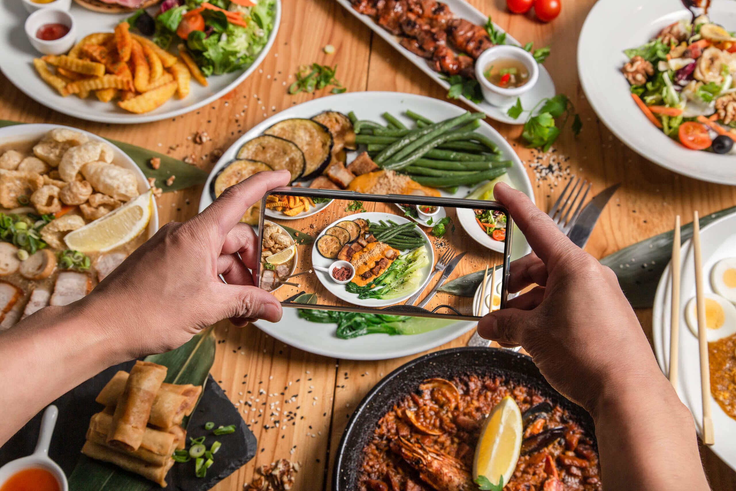 A man takes a photo of food on his smartphone at a Filipino restaurant. He shares your lifestyle on a social network.