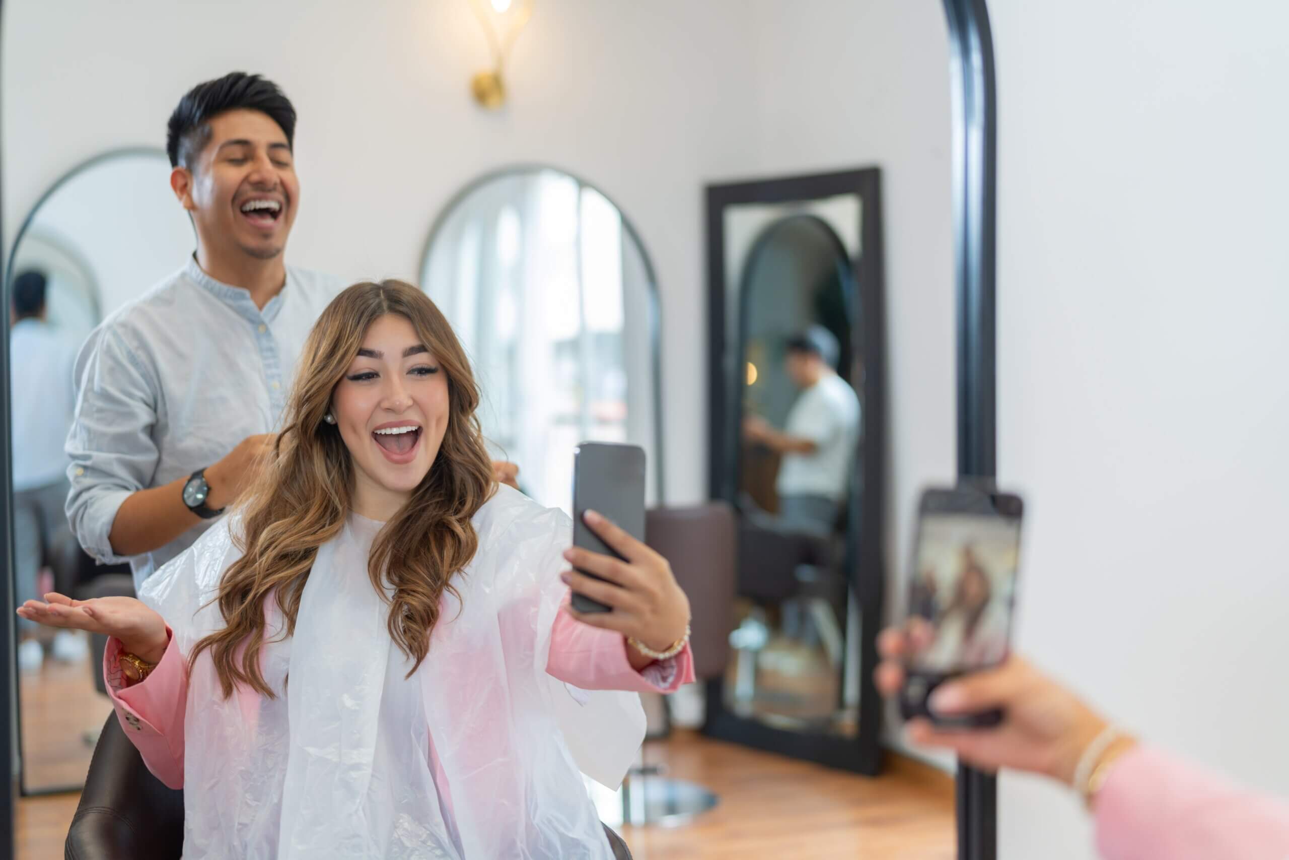 A happy female customer taking selfies in a salon with her hairstylist