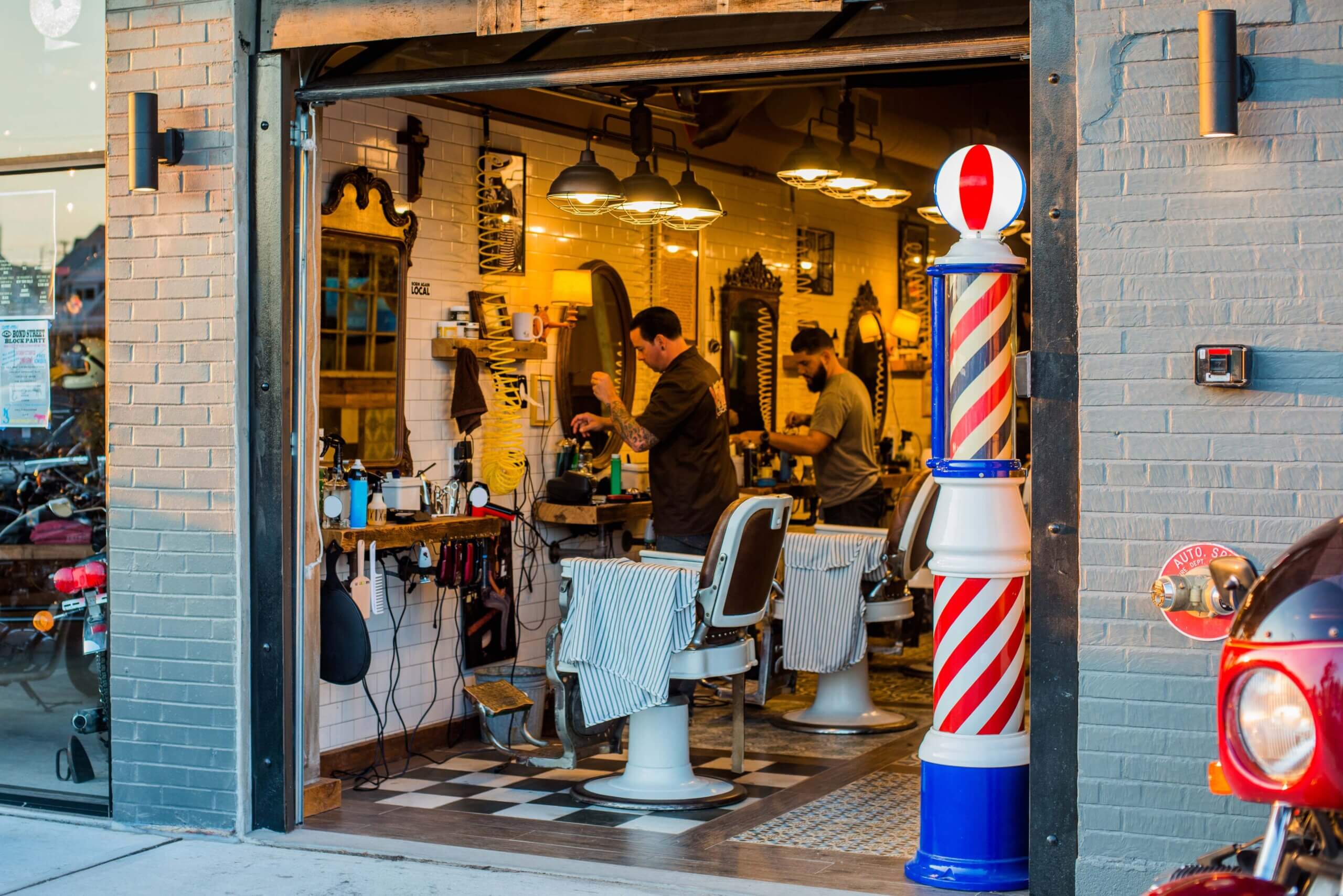 Vintage-style barbershop with barbers at work and a classic barber pole outside