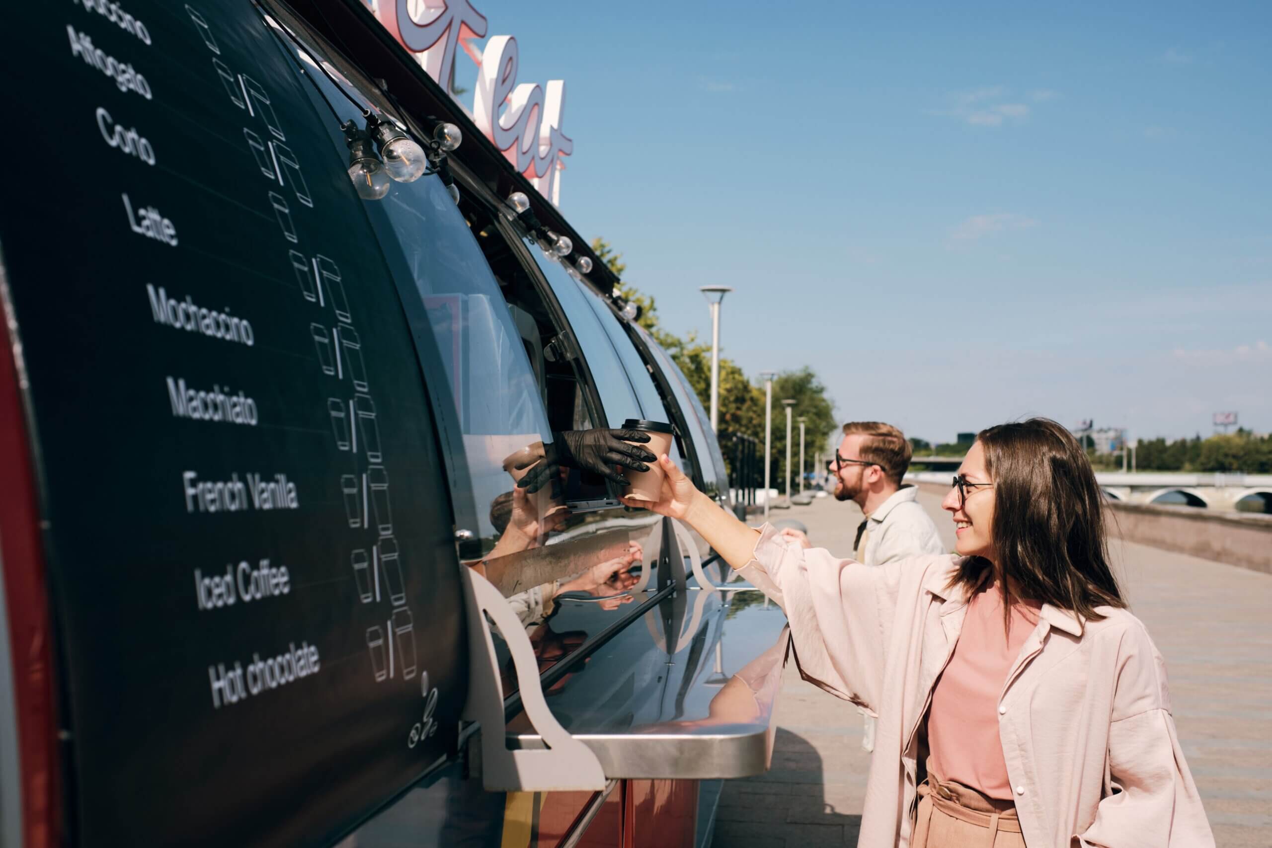 a lady buying coffee from a modern food truck